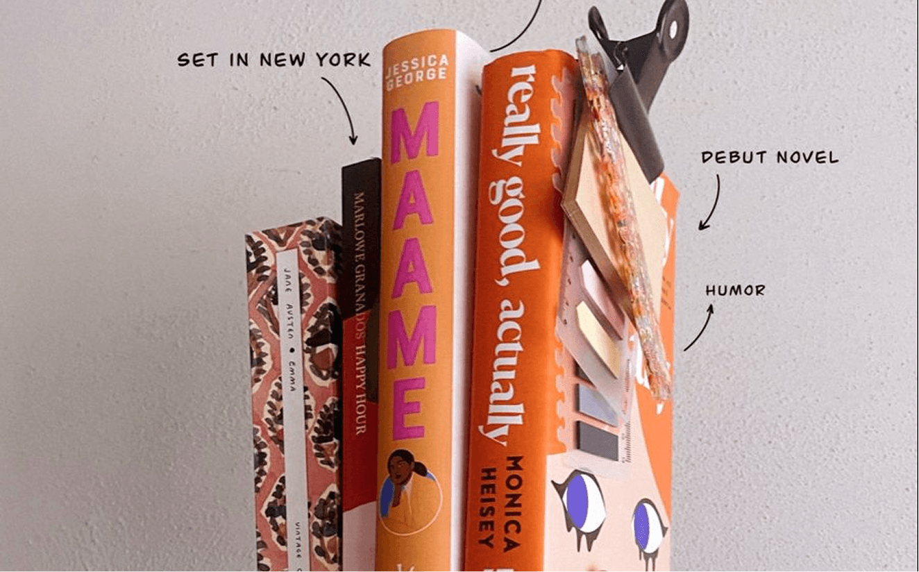 Stack of published book spines including Emma, Happy Hour, Maame, and Really Good Actually